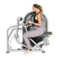 Woman using silver Hoist leg press machine with gray seat, wearing black tank top and lavender leggings, on white background