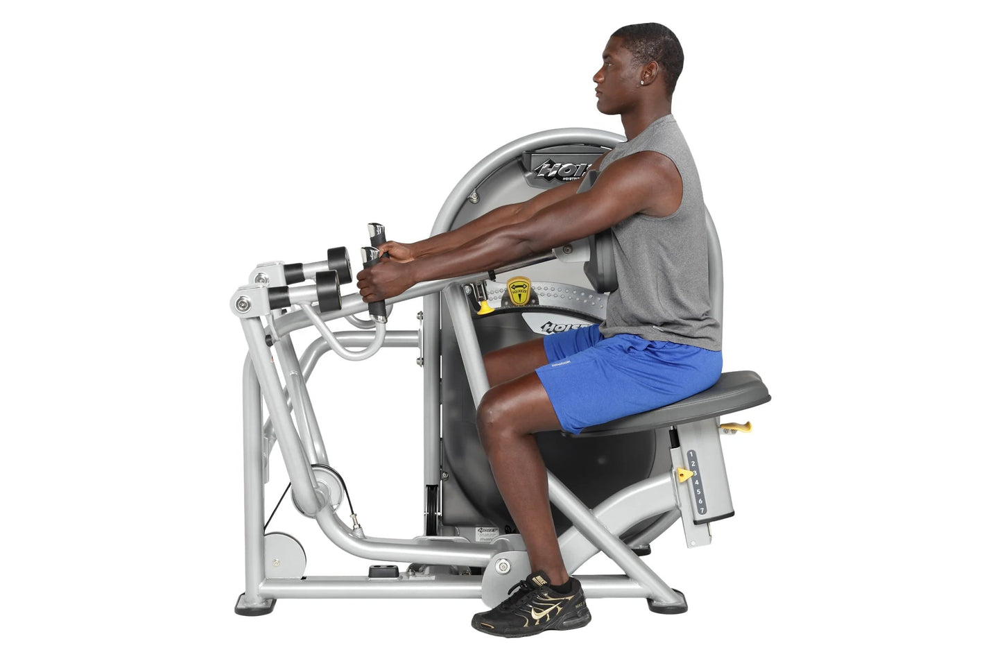 Man using Hoist Mid Row exercise machine with gray and black frame, seated position on black seat pad with blue shorts and gr