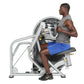 Man using Hoist mid-row exercise machine with silver frame and black seat, wearing gray sleeveless shirt and blue shorts