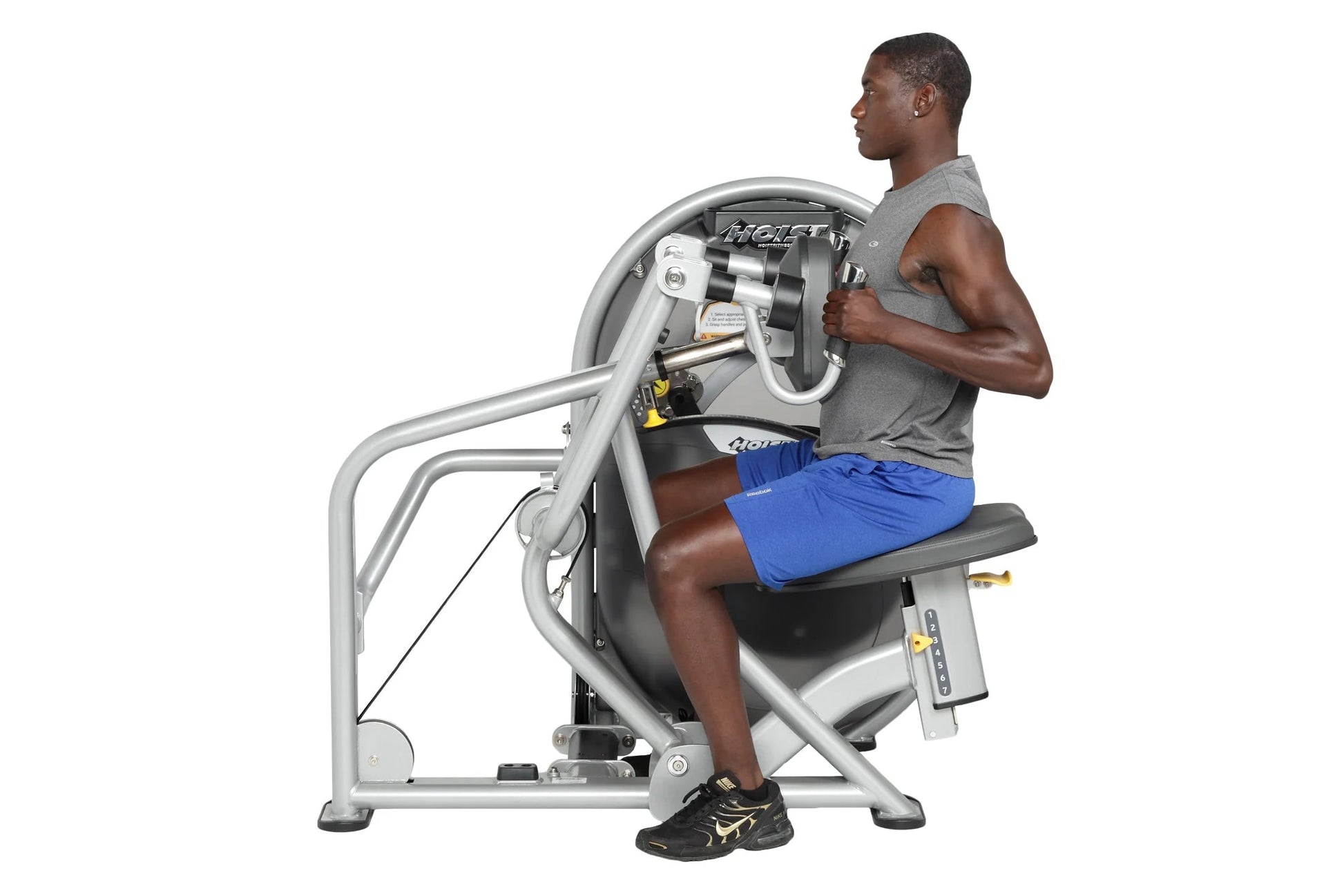 Man using Hoist mid-row exercise machine with silver frame and black seat, wearing gray sleeveless shirt and blue shorts