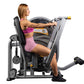 Woman in pink sports bra and shorts using gray and black Hoist chest press machine with yellow handles on white background