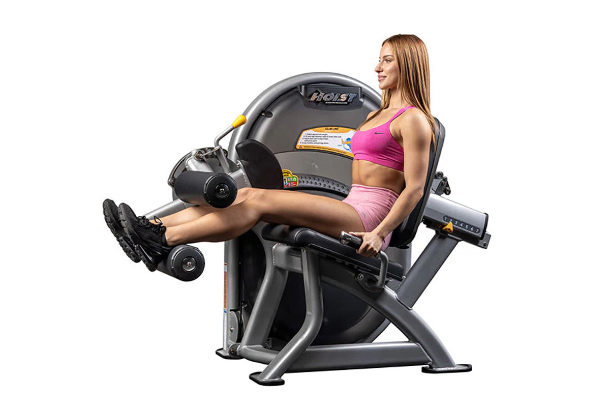 Hoist Club Line leg curl machine with gray and black frame, model CL-3402, demonstrated by woman in pink sports bra and short