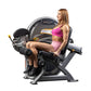 Woman in pink sports bra and shorts seated on black and gray Hoist leg curl machine with padded seat and leg extension lever