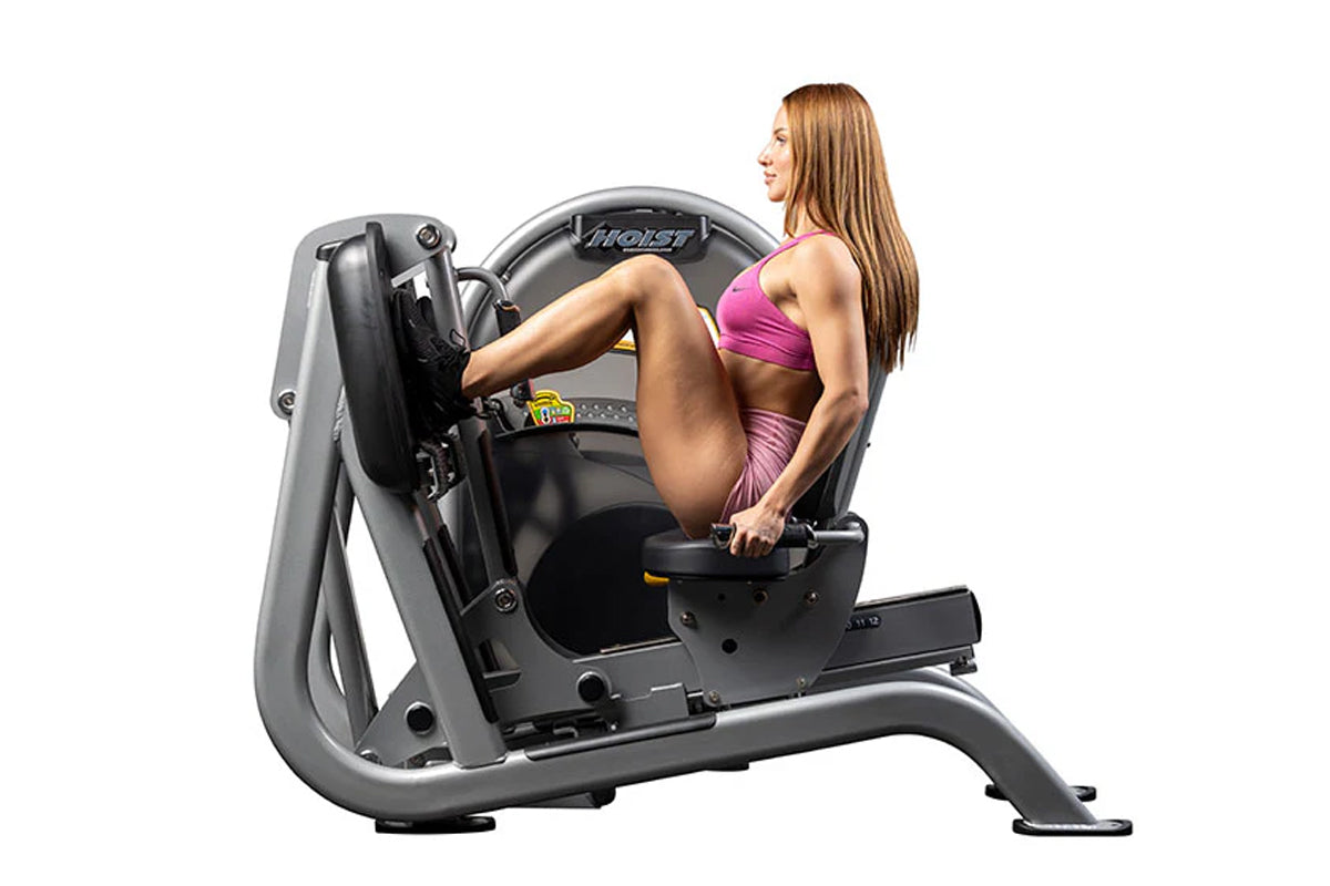 Hoist Leg Press CL-3403 exercise machine with gray frame and black seat, demonstrated by woman in pink sports bra