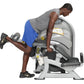 Man in gray tank top and blue shorts using white and gray leg curl machine with dumbbells on white background