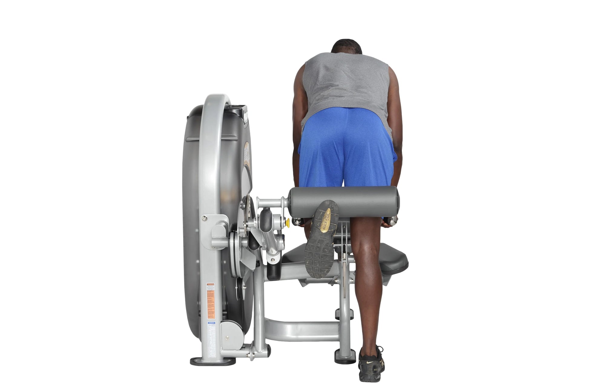 Person using gray and silver Hoist Standing/Prone Leg Curl machine, wearing gray tank top and blue shorts, on white backgroun