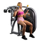 Woman using gray and black shoulder press machine with yellow handles, wearing magenta sports bra and pink shorts
