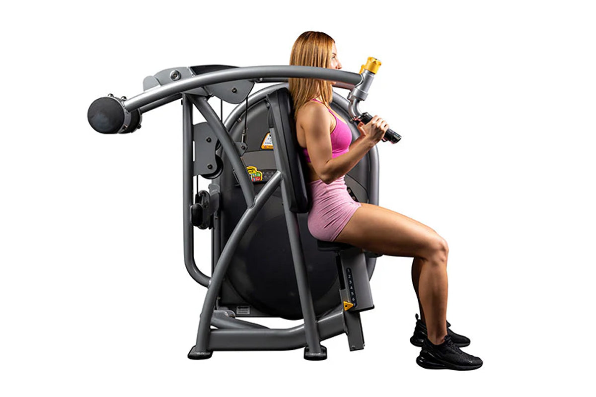 Woman in pink sports bra and shorts using black and gray Hoist Club Line shoulder press machine on white background