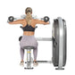 Woman performing lateral shoulder raise with dumbbells on Hoist weight machine, wearing black sports bra and lavender legging