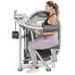 Woman using Hoist Lateral Raise machine with silver metal frame and black padded seat and armrests