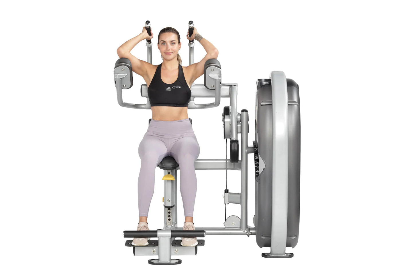 Woman using silver and gray abdominal exercise machine with weight stack, wearing black sports bra and lavender leggings