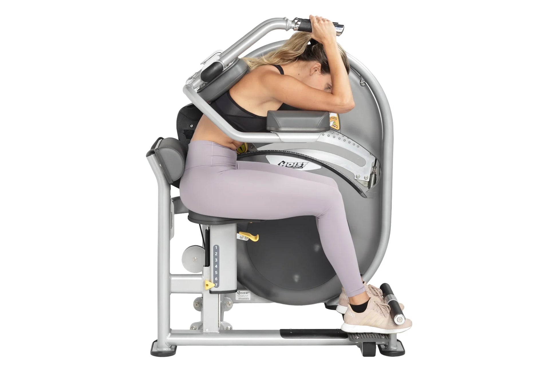 Woman using gray and black abdominal exercise machine with adjustable arm handles, seated on padded seat, wearing lavender le