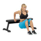 Model wearing black halter sports bra and blue shorts on Hoist flat utility bench with black and gray padding, demonstrating 