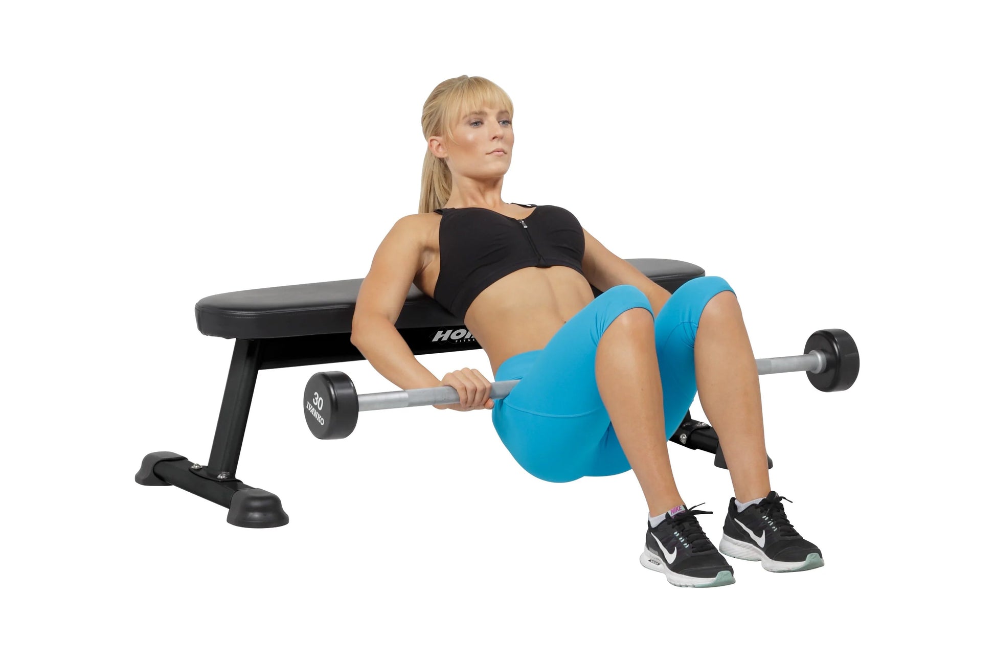 Woman exercising on black Hoist utility bench, wearing blue shorts and black sports top, holding dumbbell barbell on white ba