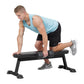 Man performing dumbbell exercise on black flat utility weight bench with padded seat and sturdy frame