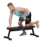 Man performing dumbbell exercise on black Hoist flat utility bench, wearing light blue tank top and black shorts
