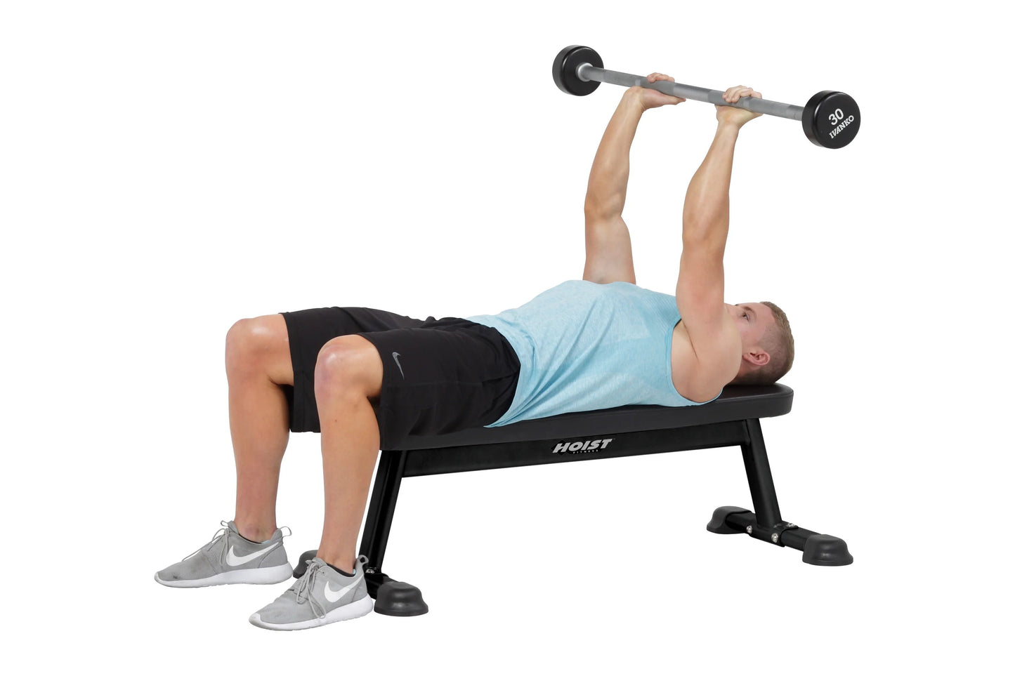 Man performing dumbbell bench press on black Hoist flat utility bench with 30-pound weights, wearing light blue shirt and bla