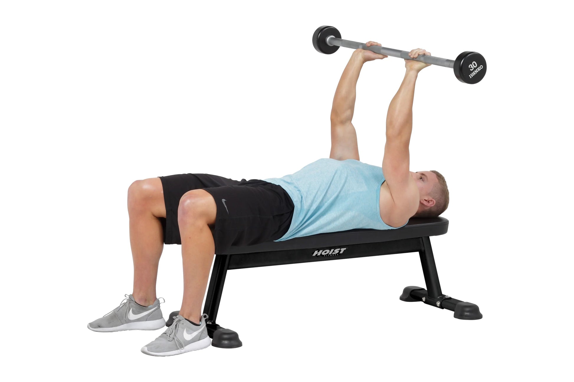 Man performing dumbbell bench press on black Hoist flat utility bench with 30-pound weights, wearing light blue shirt and bla