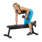 Woman performing dumbbell exercise on black Hoist flat utility bench, wearing blue leggings and black sports bra