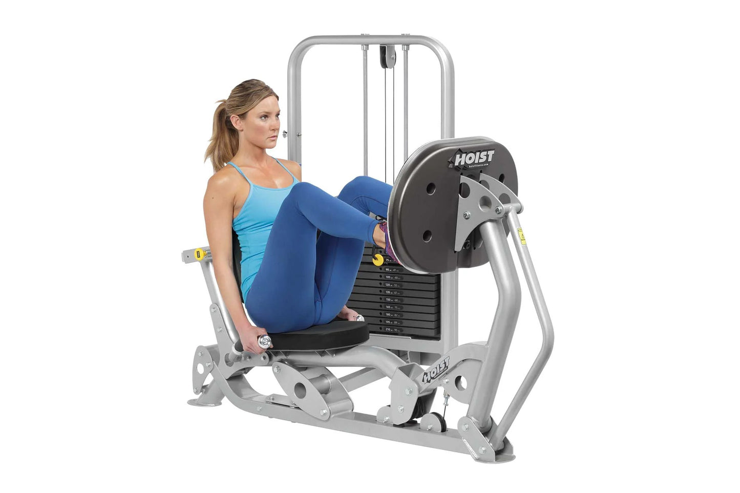 Woman using silver and black Hoist leg press machine with blue footplate and weight stack, demonstrated on white background