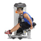 Man in blue tank top and black shorts using Hoist ab crunch machine with leg extension, white and gray frame with dark contro