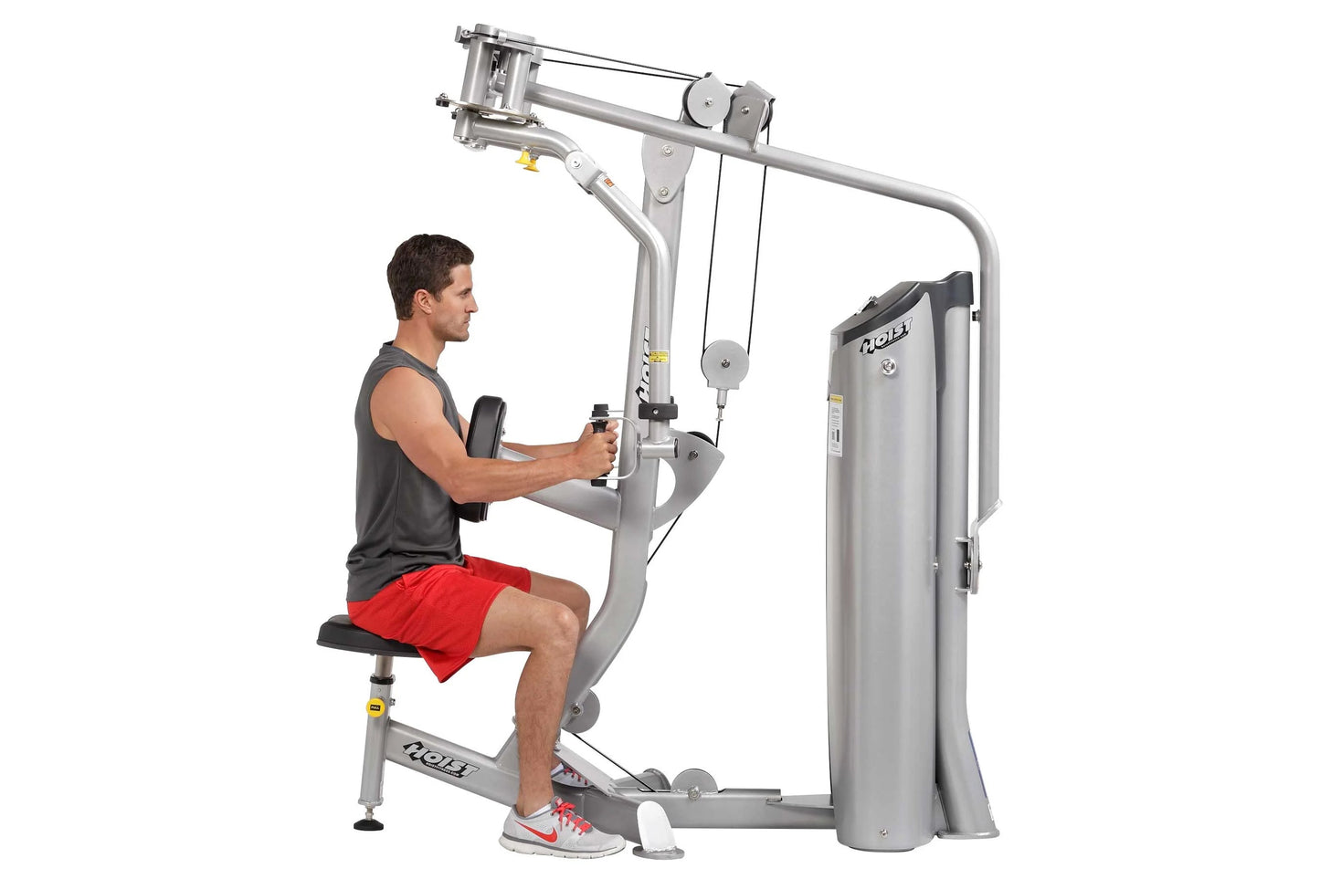 Man using silver Hoist Pec Fly/Rear Delt machine with cable arms, seated on black pad wearing gray tank top and red shorts