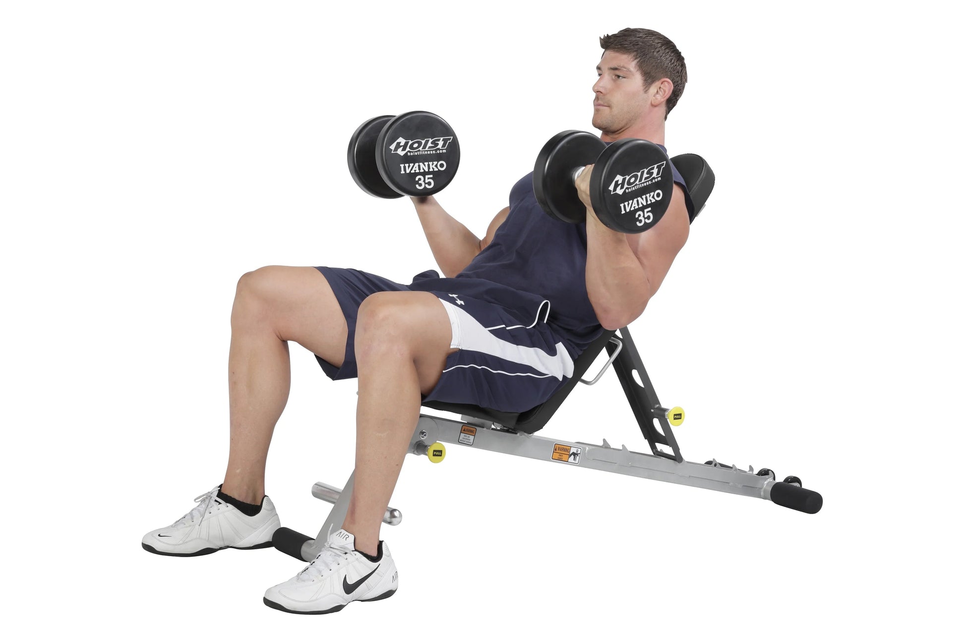 Man performing dumbbell chest press on gray Hoist Folding Multi-Bench with black 35-pound dumbbells, wearing navy shorts and 