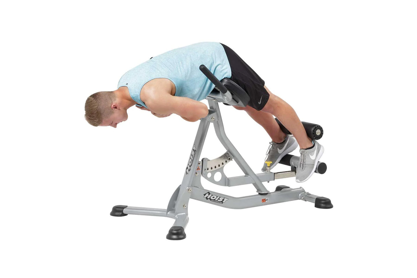 Man using gray Hoist ab and back Roman hyperextension bench with light blue shirt, performing abdominal exercise on white bac