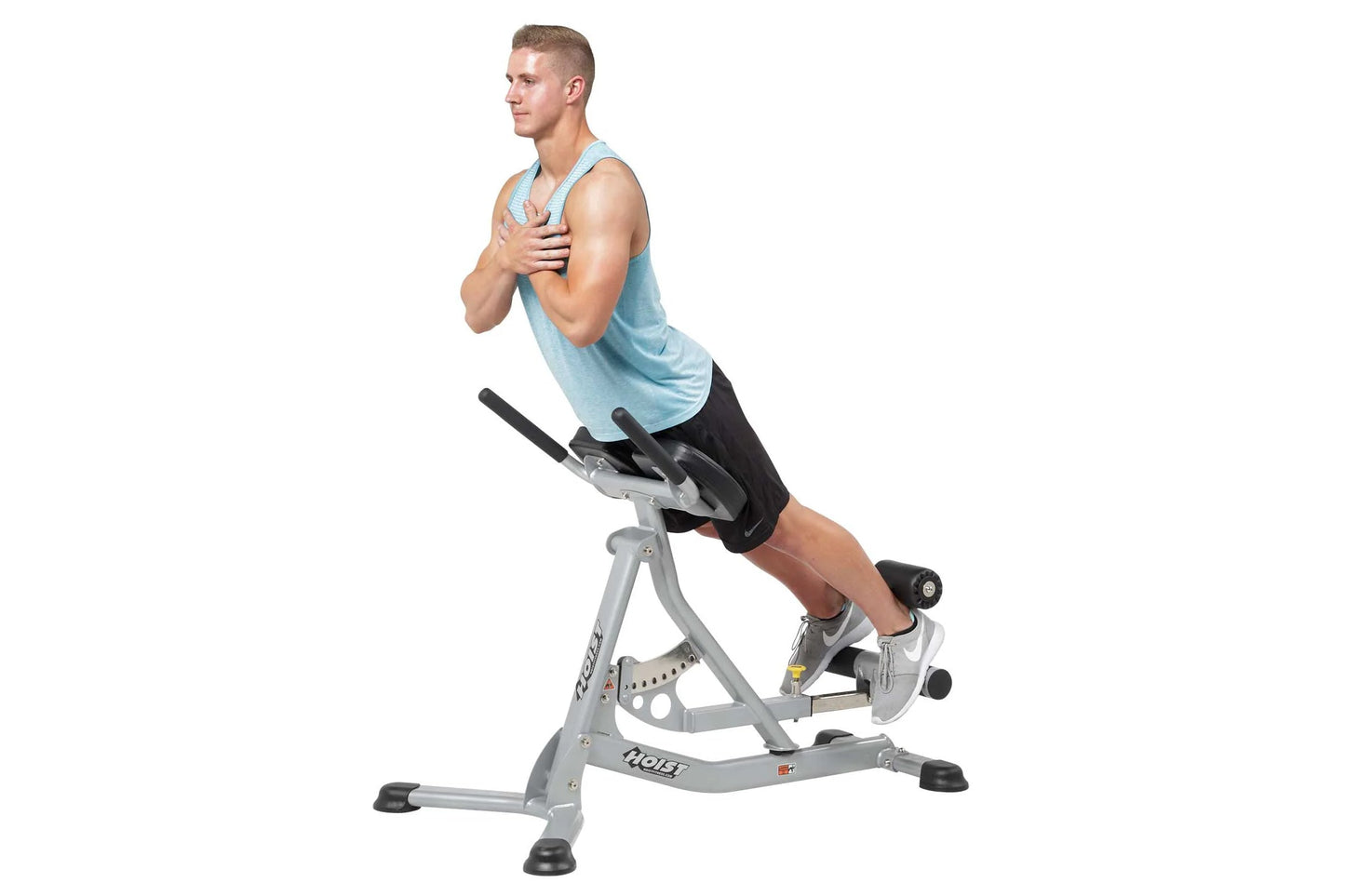 Man wearing light blue tank top and black shorts using gray and black Hoist Roman hyper bench for core exercise on white back