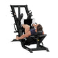 Black leg press and hack squat combo machine with padded seat and footplate, user demonstrating exercise position on white ba