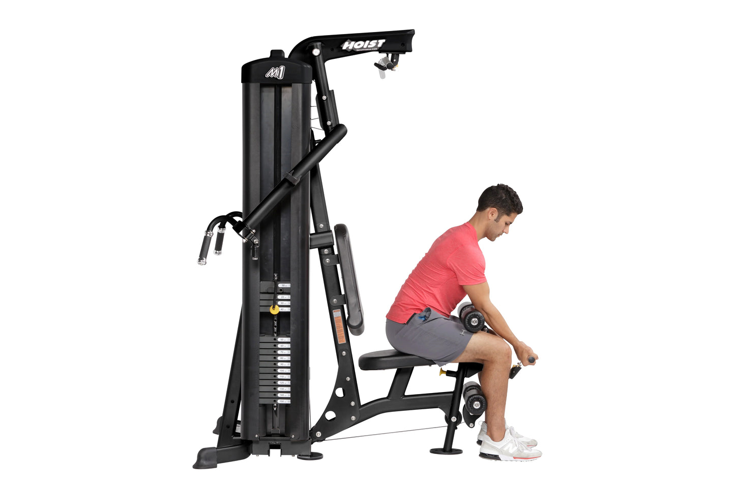 Black Hoist Mi1 home gym machine with weight stack, shown with male model in red shirt performing leg exercise on seated posi