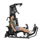 Hoist Mi1 black multi-station home gym machine with seated male model demonstrating leg press position, white background