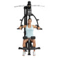 Woman in light blue tank top using black Hoist Mi1 home gym machine with horizontal handles and foot platform on white backgr