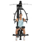Black and silver home gym machine with chest press and leg press functions, model seated wearing light blue tank top and whit
