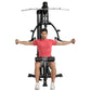 Man in red t-shirt using black Hoist Mi1 home gym machine with extended arms on white background