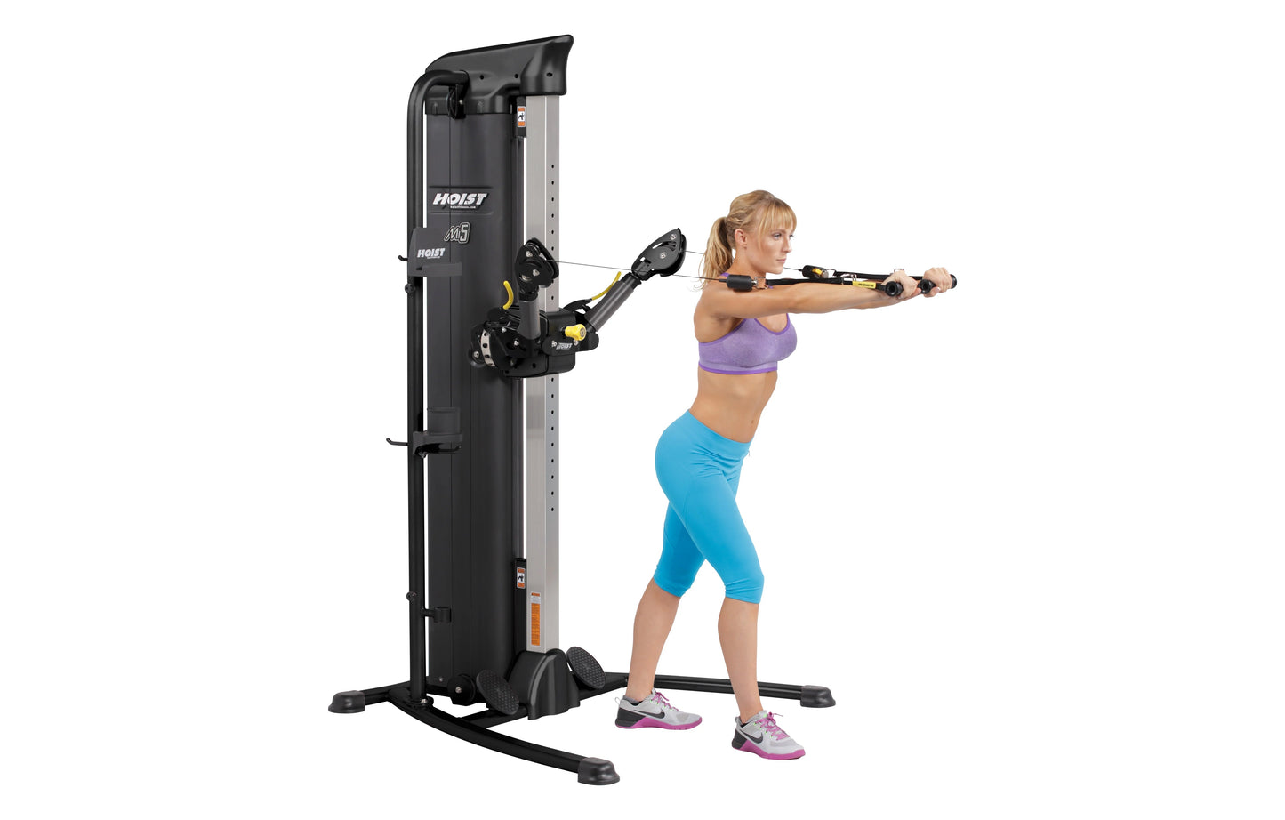 Hoist Mi5 Functional Trainer with black and silver frame, shown in use by female model in purple sports bra and blue capris