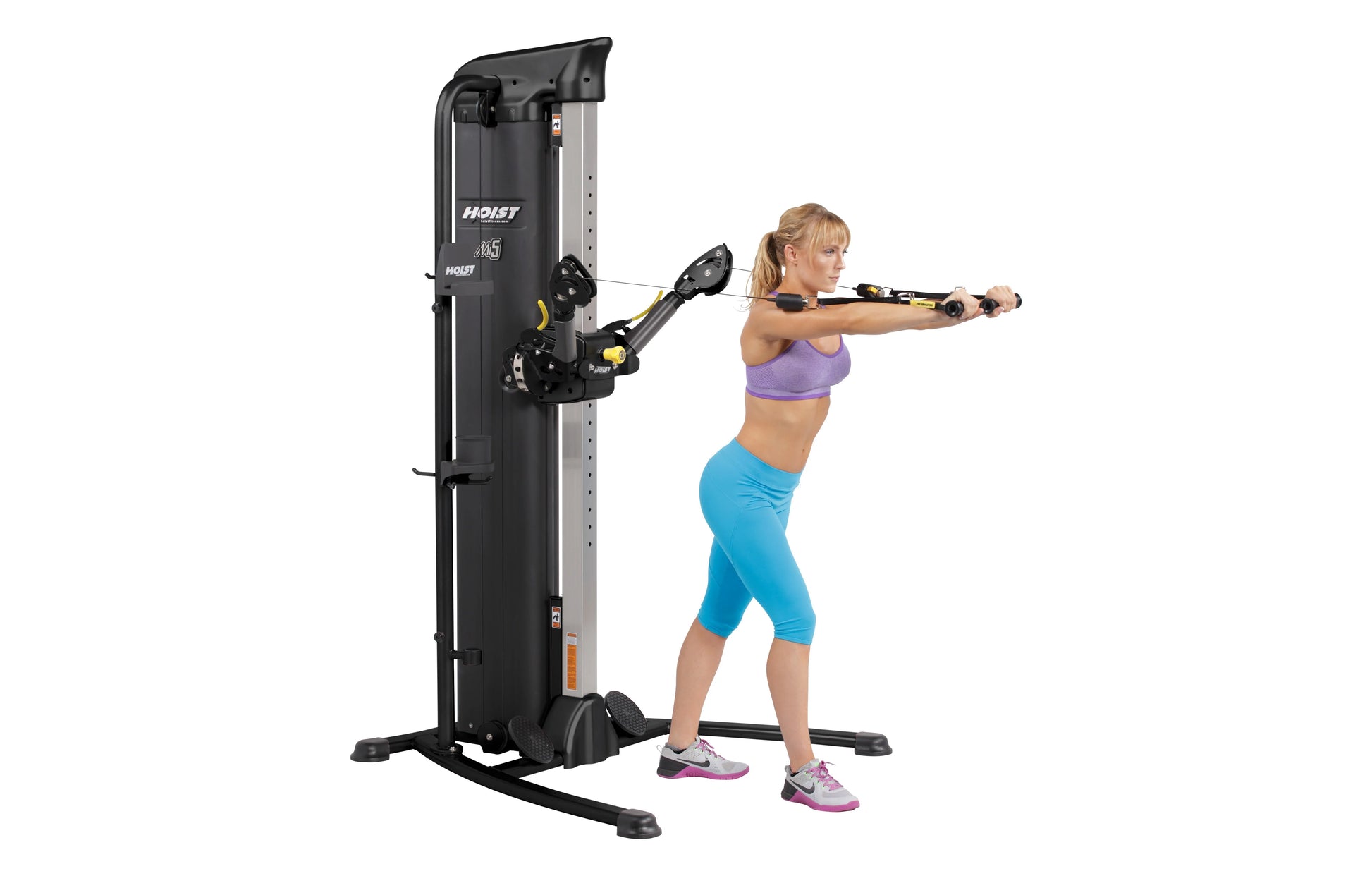 Hoist Mi5 Functional Trainer with black and silver frame, shown in use by female model in purple sports bra and blue capris