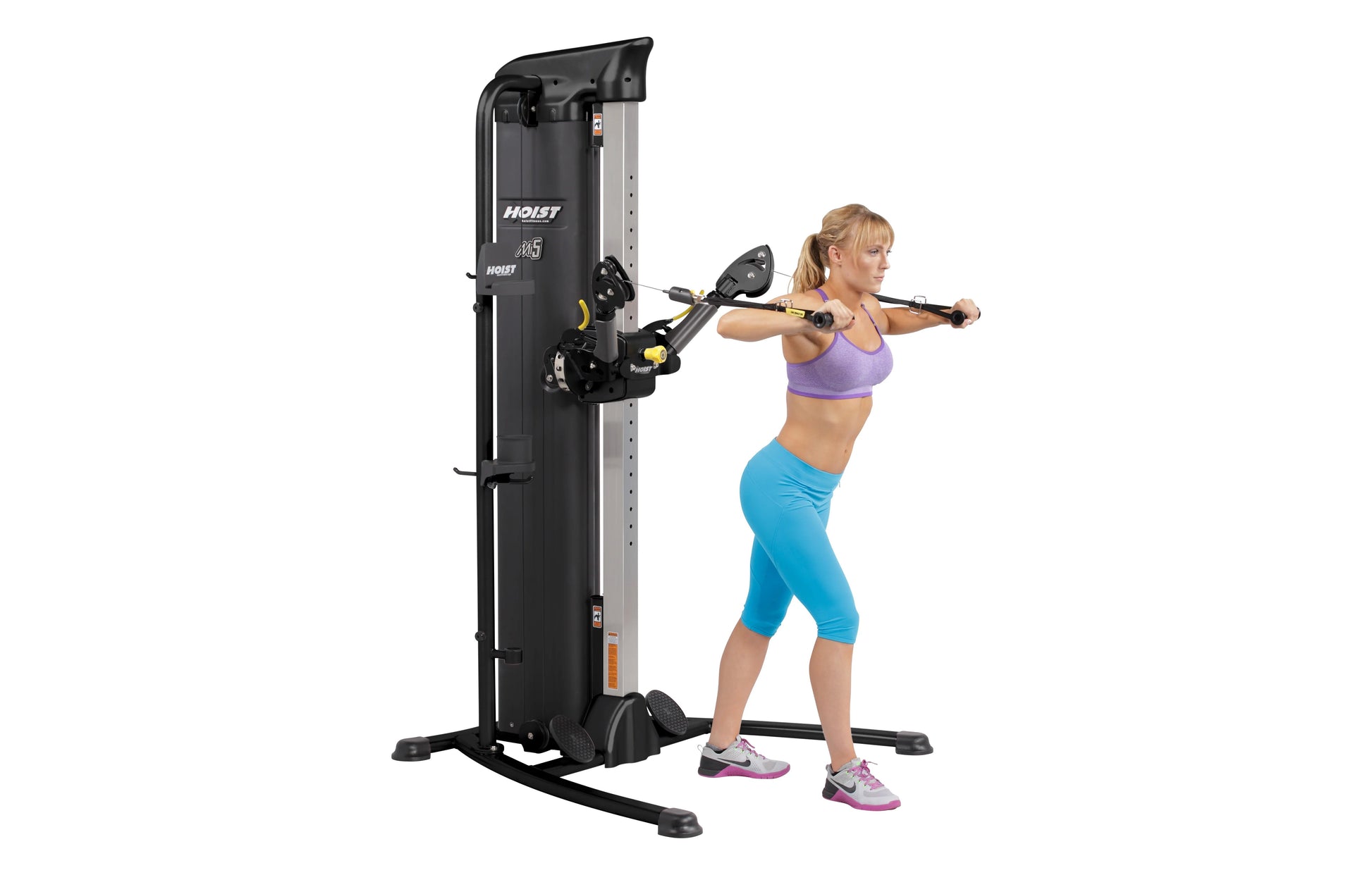 Hoist Mi5 functional trainer with black frame and gray accents, shown being used by a woman in purple sports bra and blue cap