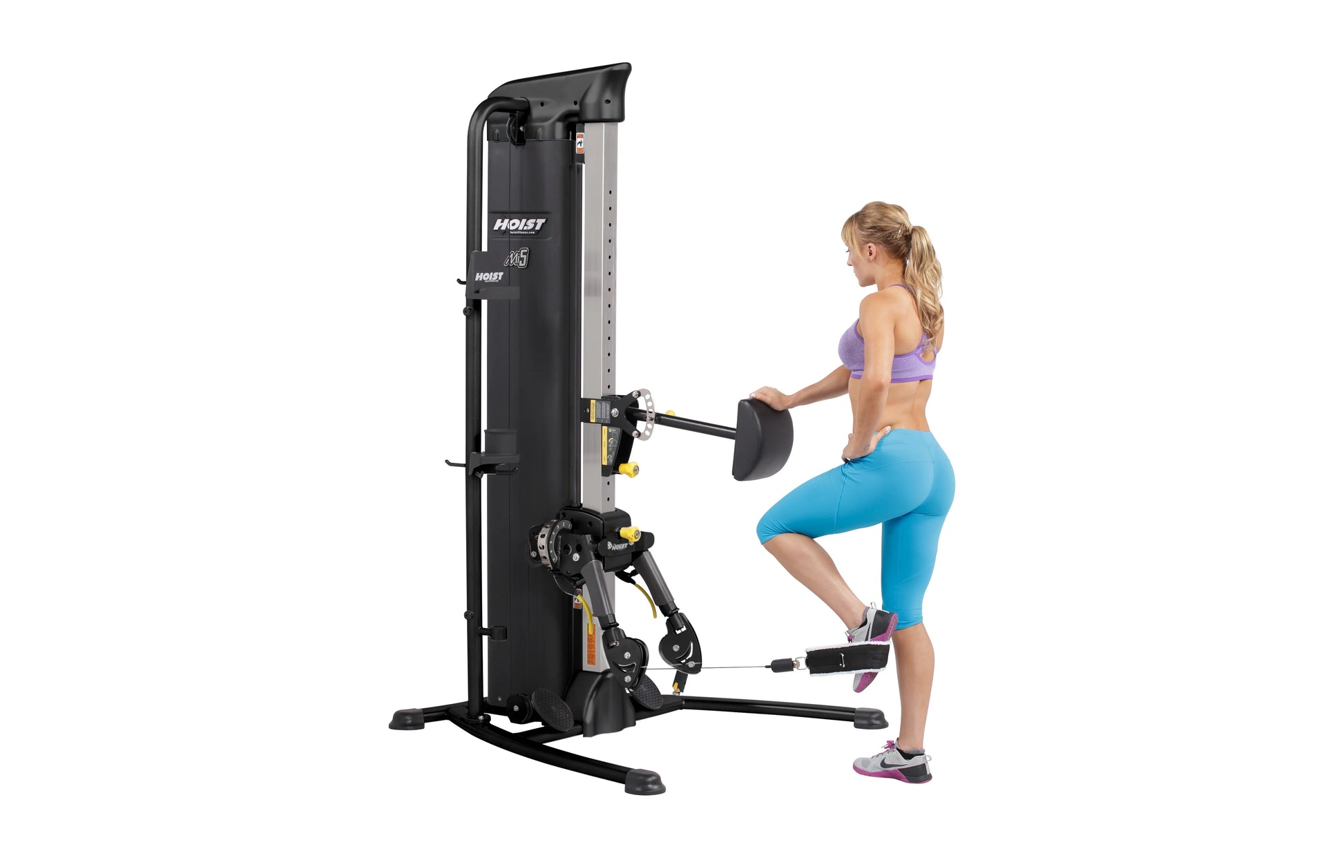 Hoist Mi5 functional trainer with black and silver frame, model shown with woman performing leg exercise on white background
