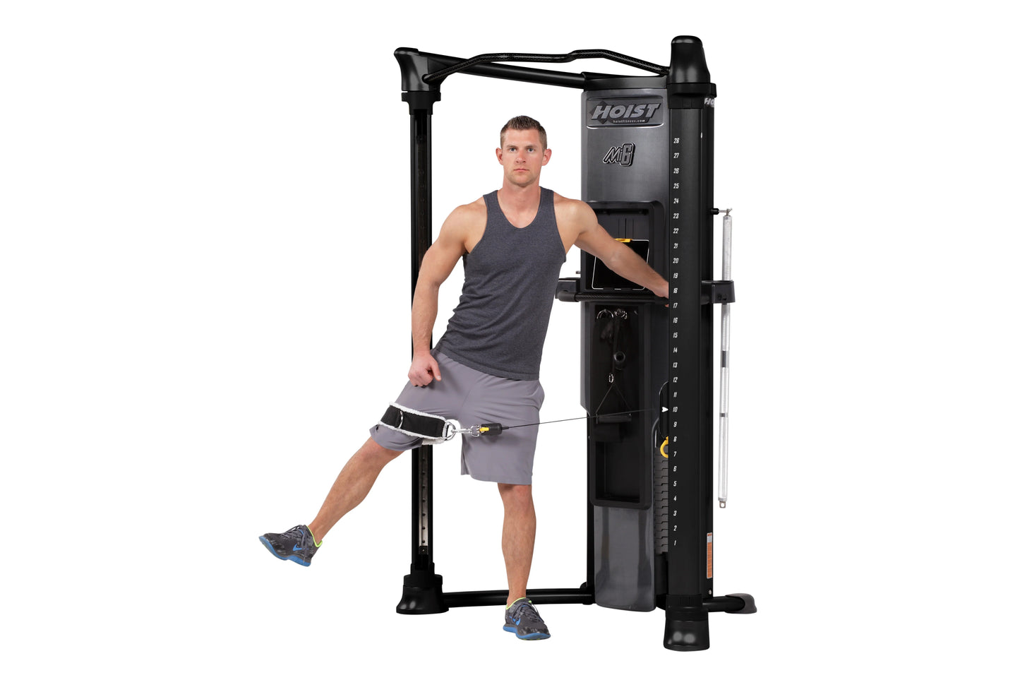 Hoist Mi6 black functional trainer home gym with male model demonstrating leg exercise using cable attachment