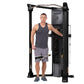 Male model demonstrating Hoist Mi6 functional trainer with dual weight stacks, black frame and cables, on white background
