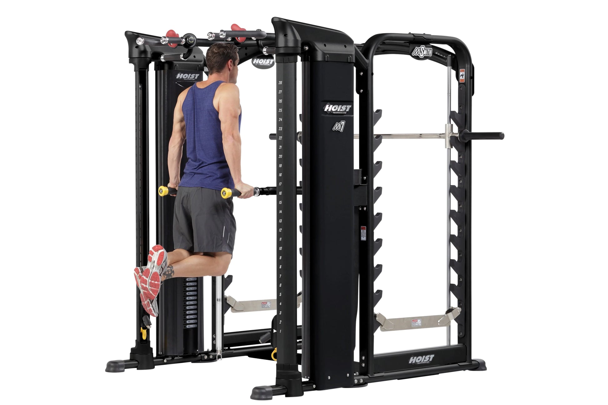 Man in blue tank top using black Hoist MI7 Smith functional trainer with red accents and yellow dumbbells, on white backgroun