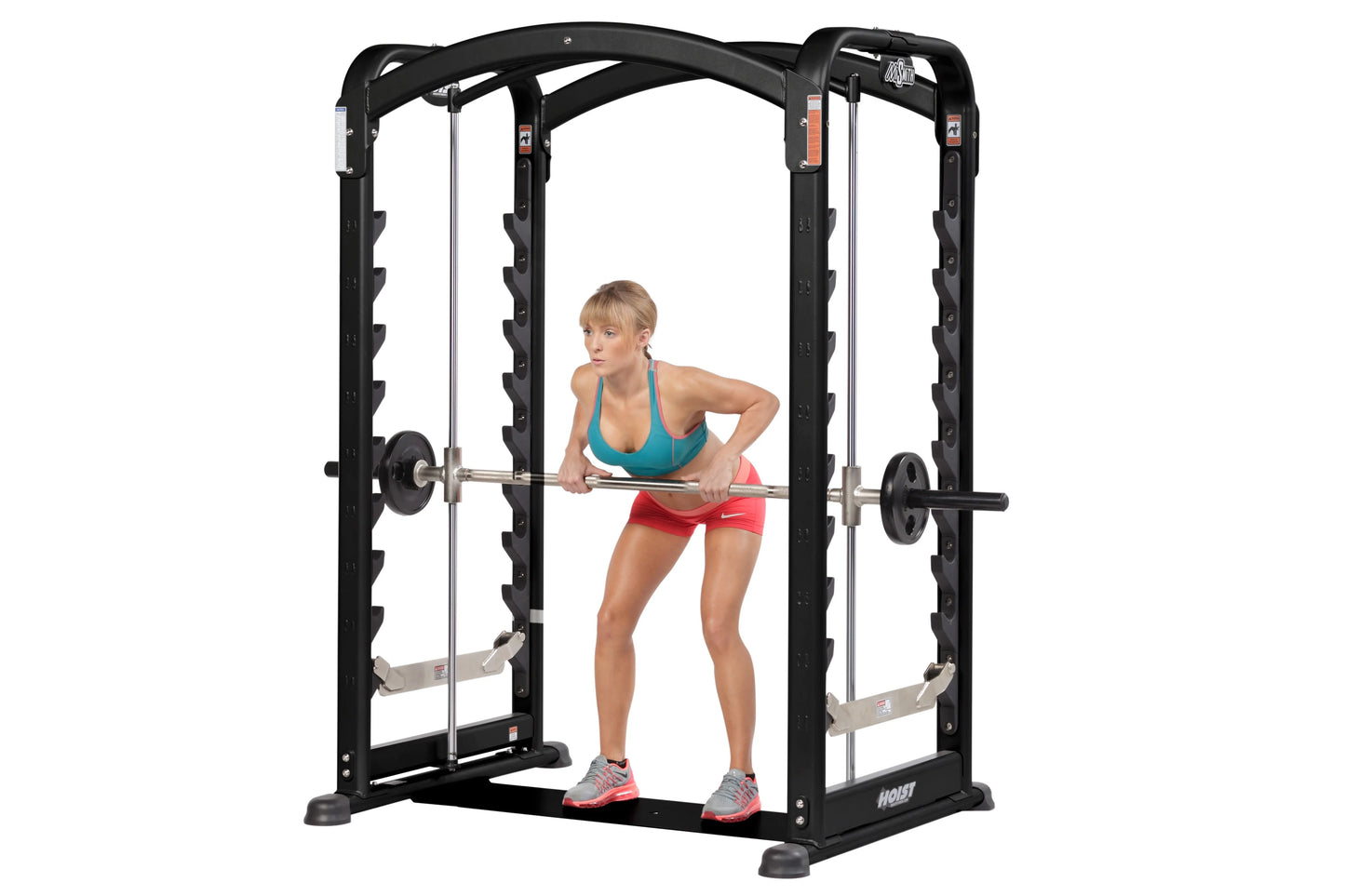 Black Hoist Smith machine with dual chrome bars, shown with woman performing barbell exercise wearing teal sports bra and red