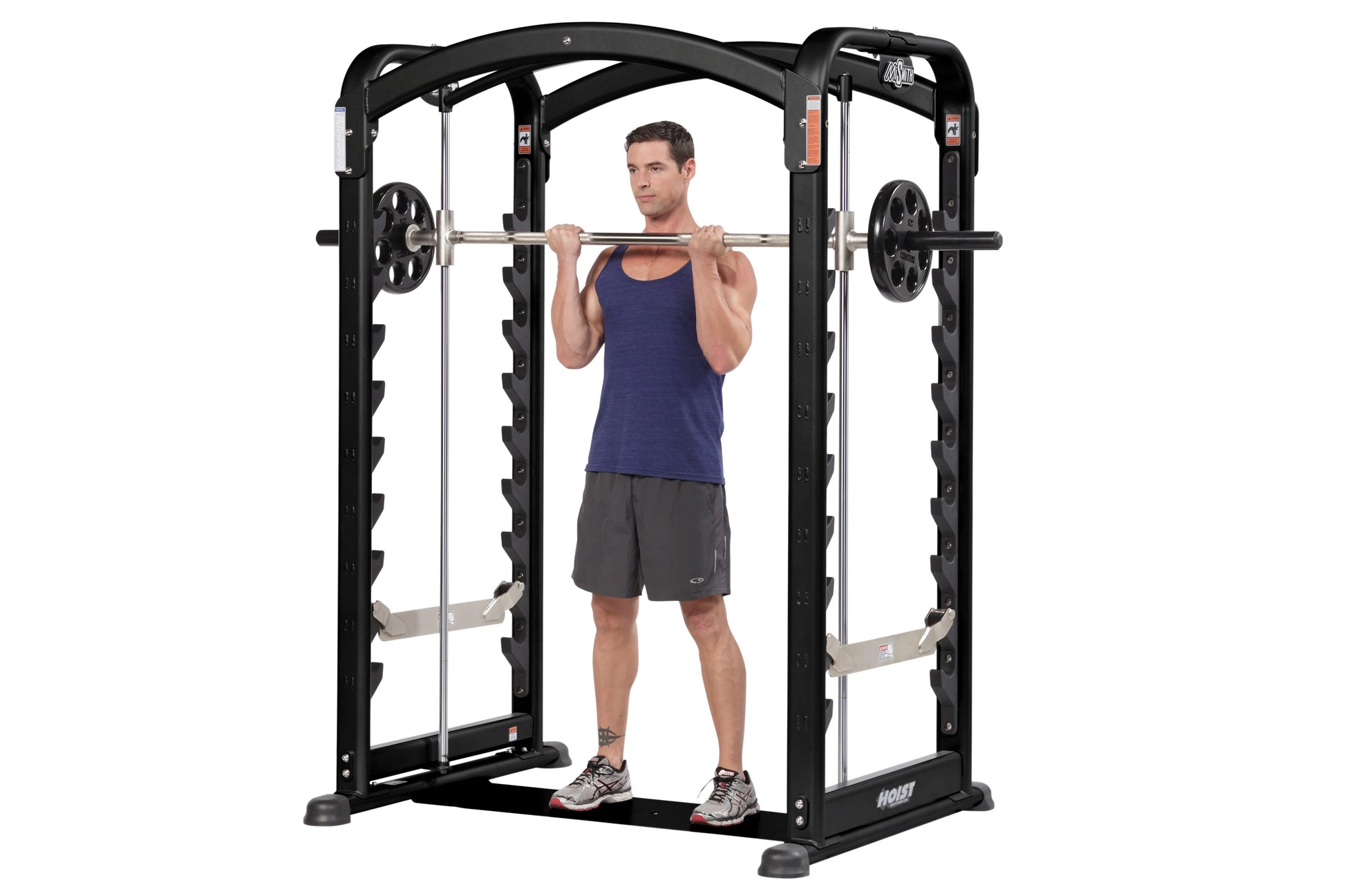 Black and silver Hoist Smith machine with dual action design, demonstrated by male model in navy tank top lifting barbell wit