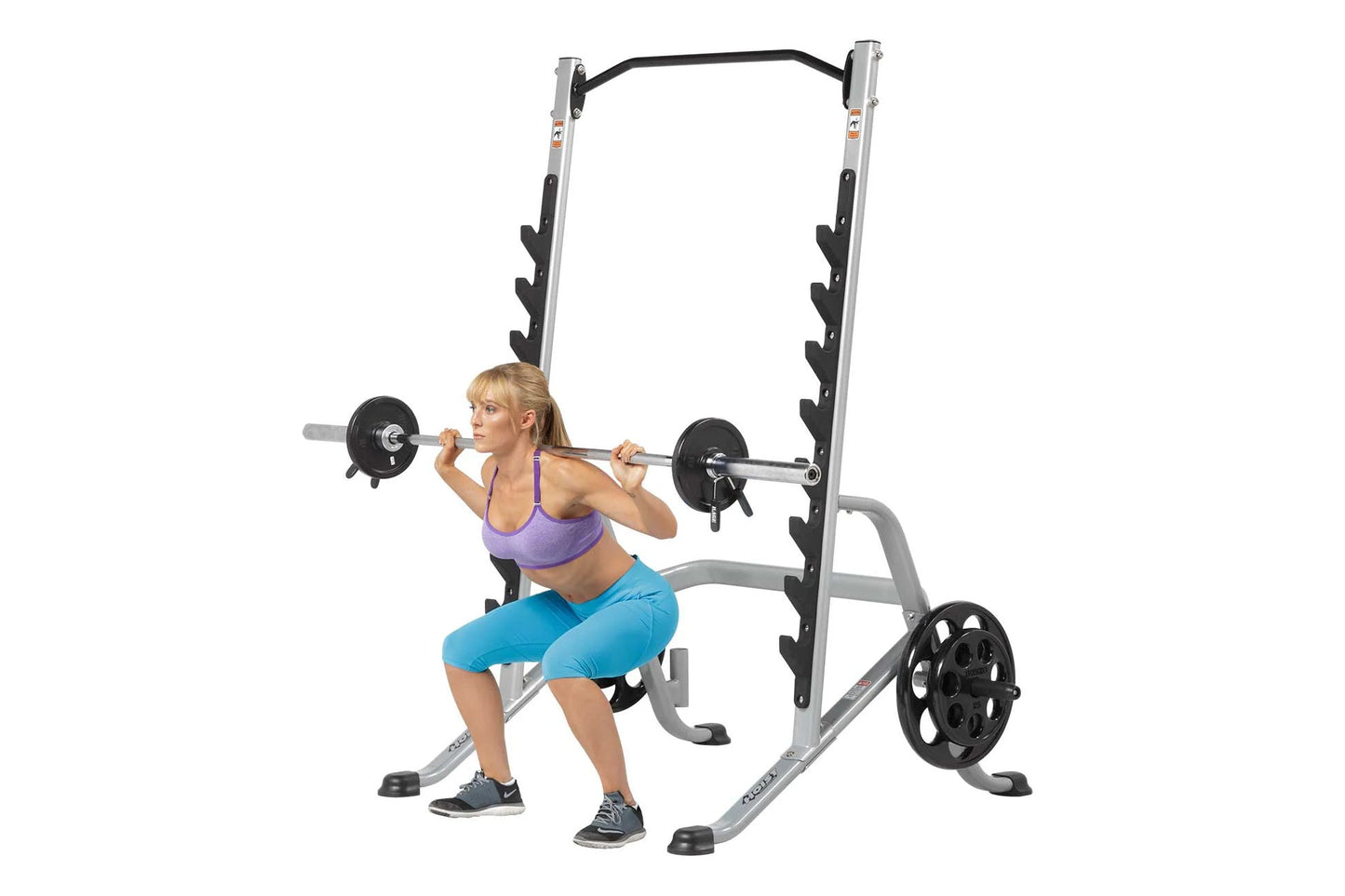 Silver and black multi-purpose squat rack with barbell and weight plates, shown with model performing squat exercise