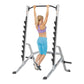 Silver and black multi-purpose squat rack with pull-up bar, shown with woman demonstrating pull-up exercise on white backgrou