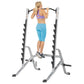 Woman using silver and black multi-purpose squat rack with adjustable barbell, worn with purple sports bra and blue capri leg