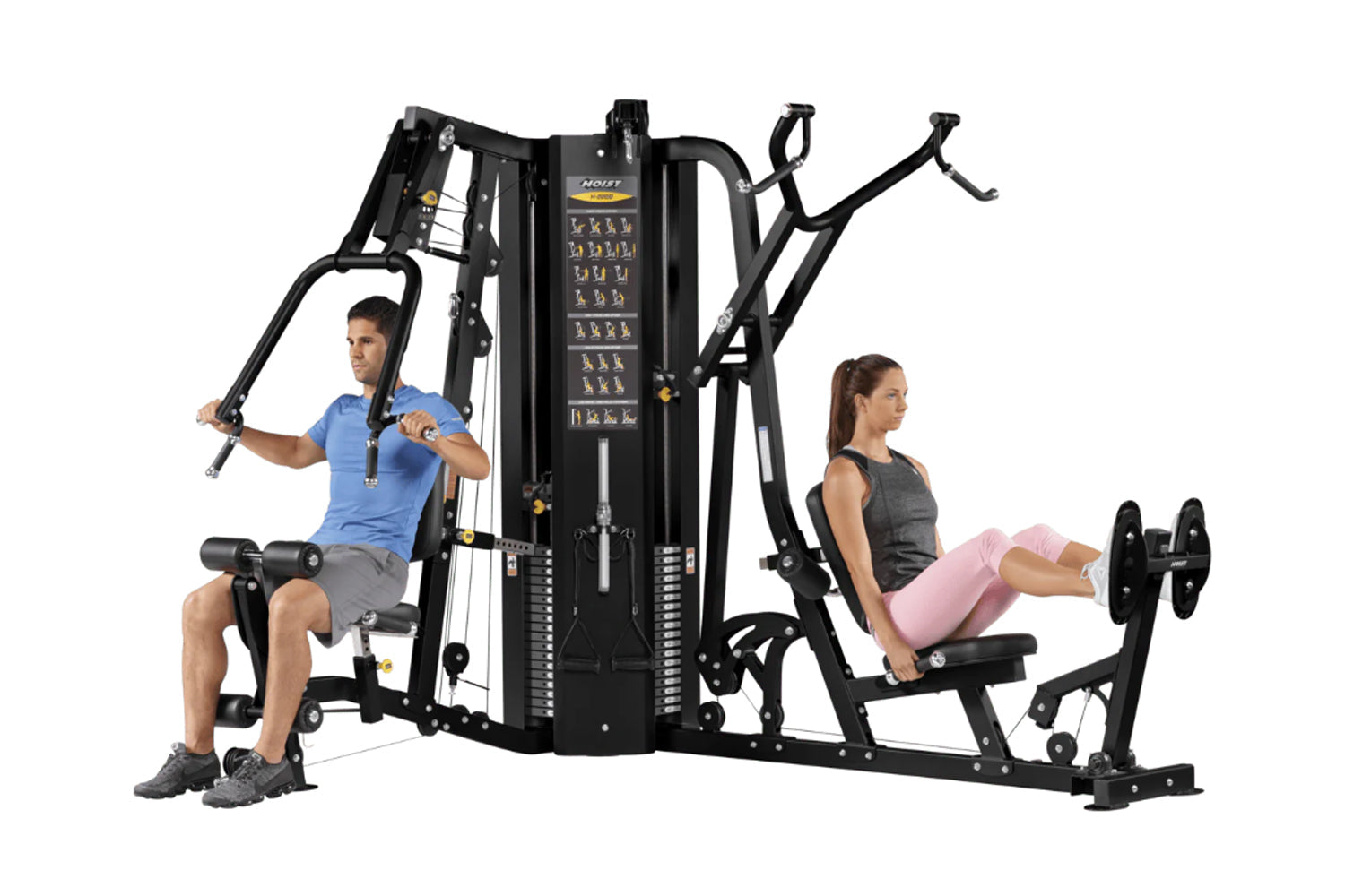 Black multi-station gym equipment with two users demonstrating exercises, featuring stacked weight plates and instruction pan