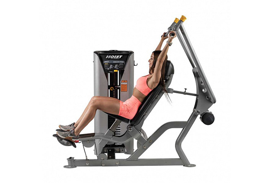 Hoist ROC-IT shoulder press machine with gray steel frame and black seat, woman in pink sports bra demonstrating upper body e