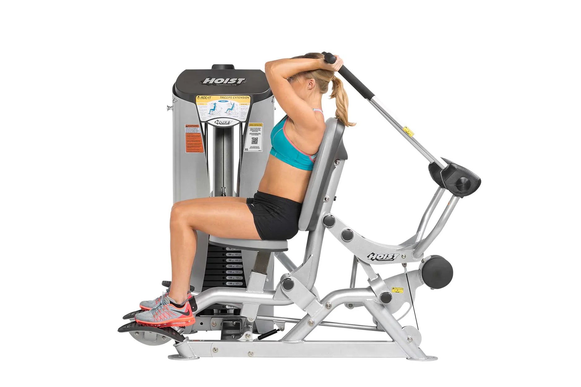 Woman using Hoist ROC-IT Triceps Extension Machine with silver frame and black seat, demonstrating triceps extension exercise